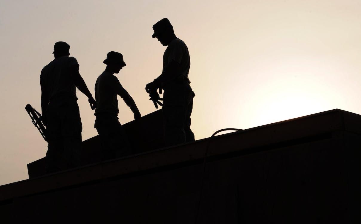 The silhouette of restoration workers on a roof.