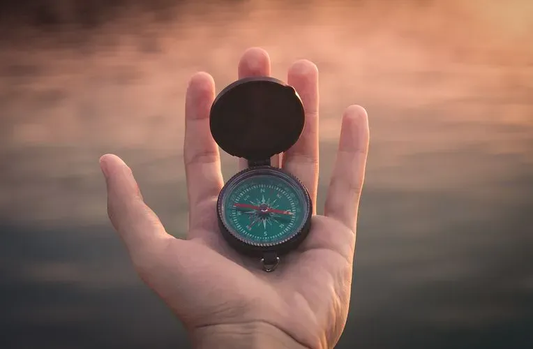 A hand holds a compass.