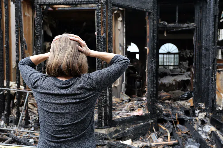 A distressed woman looking at a burned-down building.