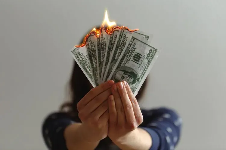 Hands holding cash on fire.