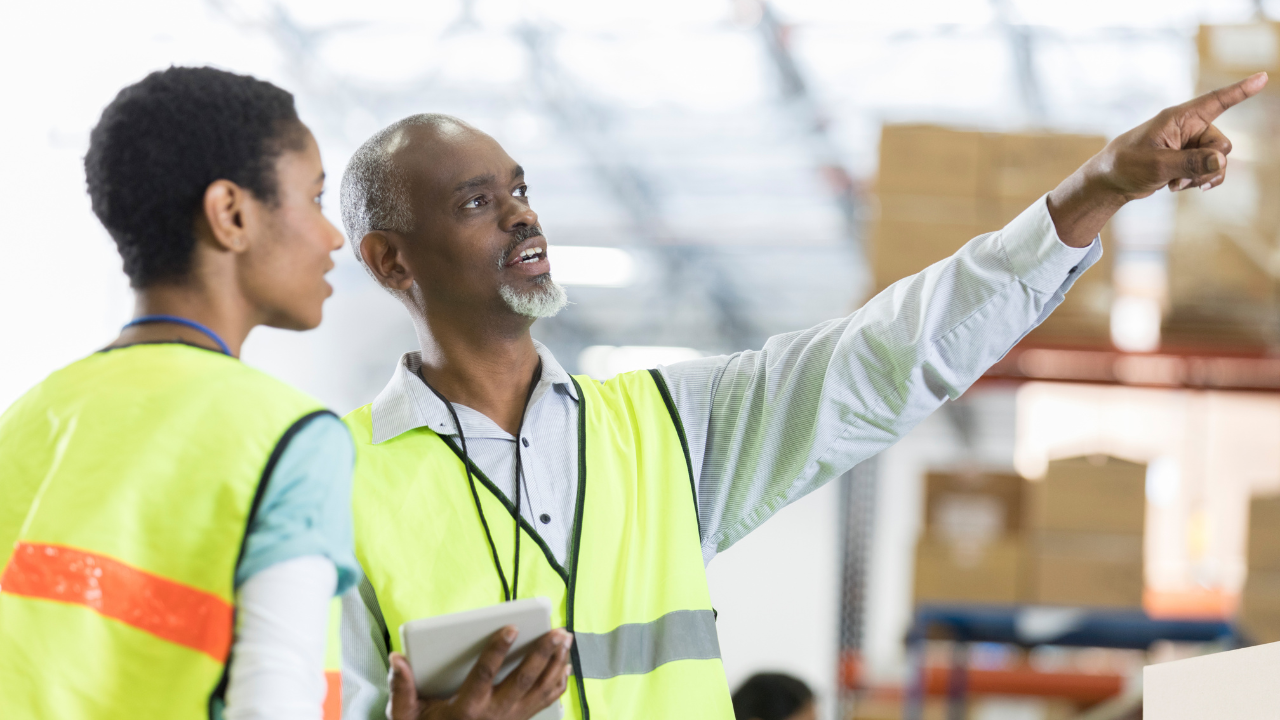 2 factory workers pointing in the air