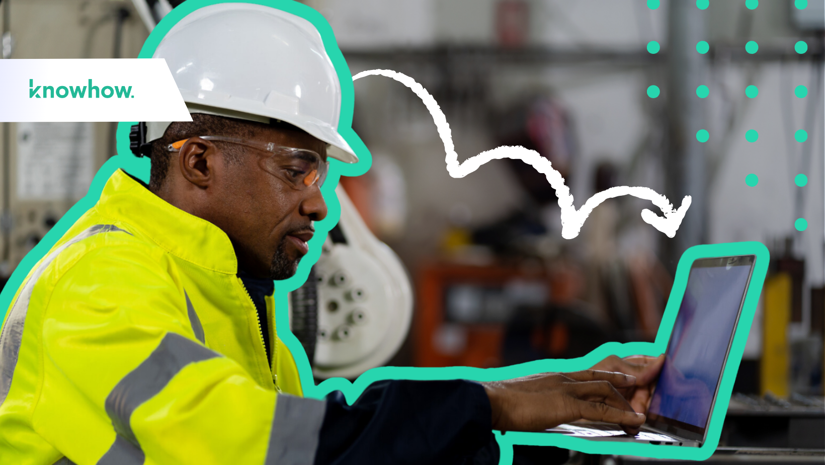 factory worker wearing a hard hat typing on a computer in a factory