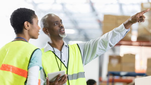 2 factory workers pointing in the air