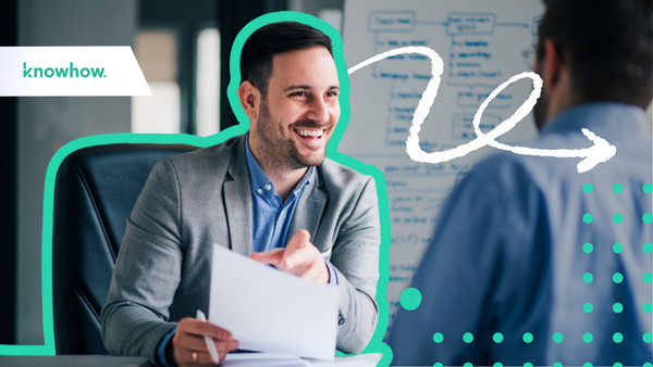A man sitting at a desk smiling and talking to somebody